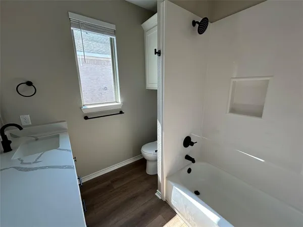 a bathroom with a double vanity sink and mirror with wooden floor