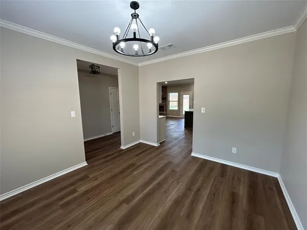 a view of kitchen and empty room with wooden floor