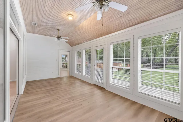 a view of an empty room with a window and wooden floor