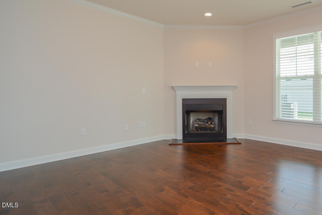 1803 Grandmaster Way Wake Forest, NC 27587 - Photo 6 of 26 an empty room with wooden floor fireplace and windows