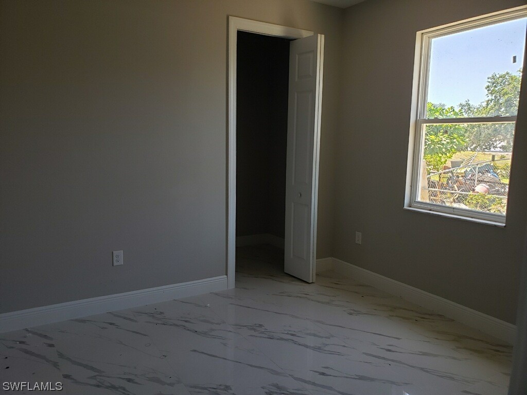 2715 50th Street Southwest Lehigh Acres, FL 33976 - Photo 8 of 16 an empty room with wooden floor and windows