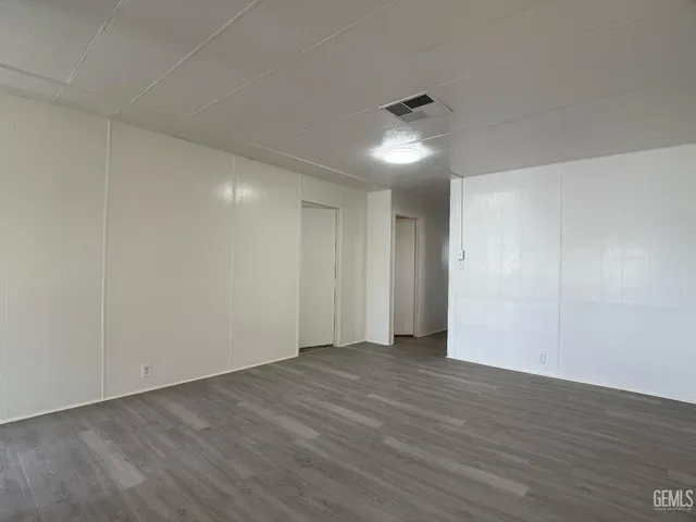 a view of an empty room with wooden floor and ceiling fan