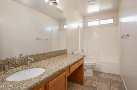 a bathroom with a granite countertop sink a toilet a mirror and shower