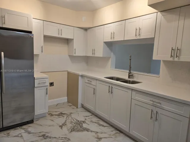 a kitchen with stainless steel appliances granite countertop a sink and a refrigerator