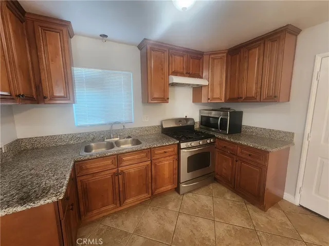 a kitchen with stainless steel appliances granite countertop a stove a sink and a microwave