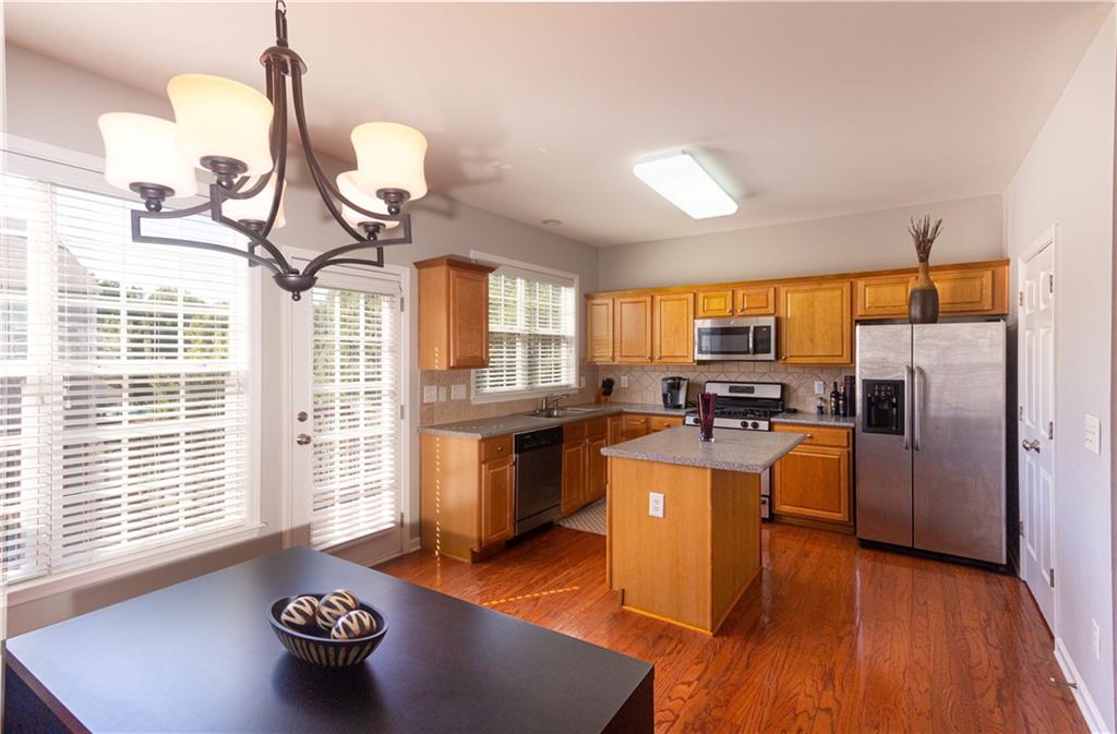 1035 Thornborough Drive Alpharetta, GA 30004 - Photo 2 of 14 a kitchen with stainless steel appliances a stove a refrigerator a sink a dining table and chairs