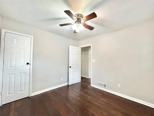 an empty room with wooden floor and ceiling fan