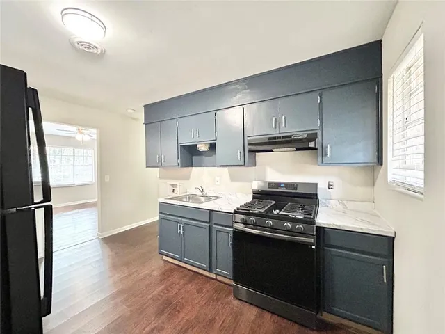 a kitchen with a refrigerator stove and wooden floor