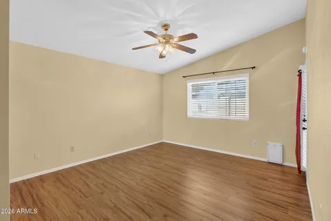 a view of an empty room with wooden floor and a window