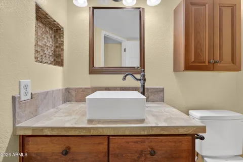 a bathroom with a granite countertop sink a mirror and a toilet