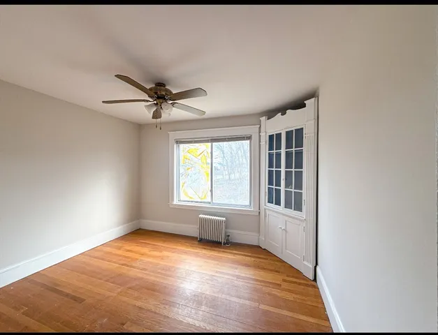 a view of empty room with wooden floor and fan