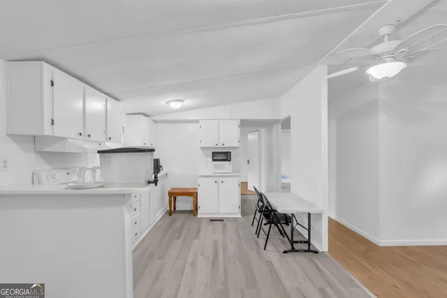 a kitchen with white cabinets and chairs