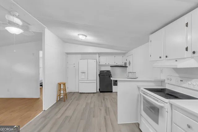 a kitchen with a sink a stove a refrigerator and white cabinets