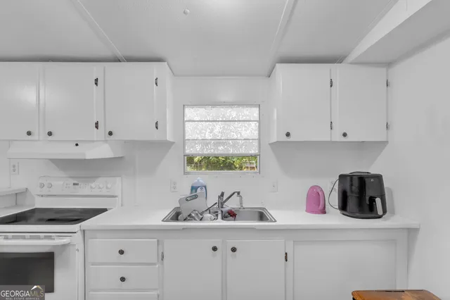 a kitchen with white cabinets white appliances and sink