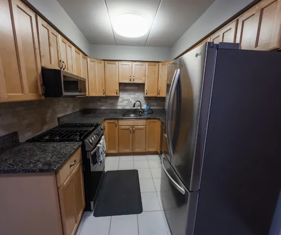 a kitchen with stainless steel appliances granite countertop a refrigerator a stove a sink and a microwave