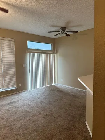 an empty room with windows and ceiling fan