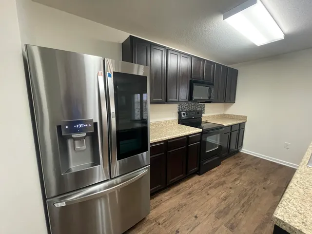 a kitchen with stainless steel appliances wooden cabinets and wooden floor