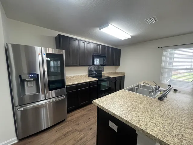a kitchen with kitchen island a counter space a sink appliances and cabinets