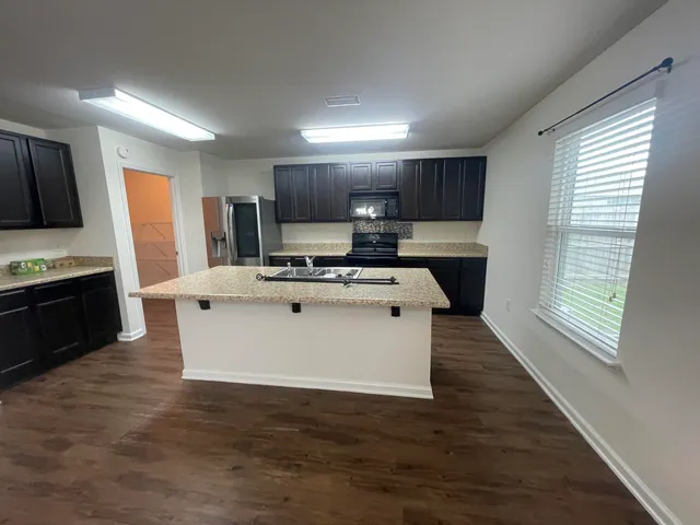 a large kitchen with kitchen island a stove a sink a refrigerator and cabinets