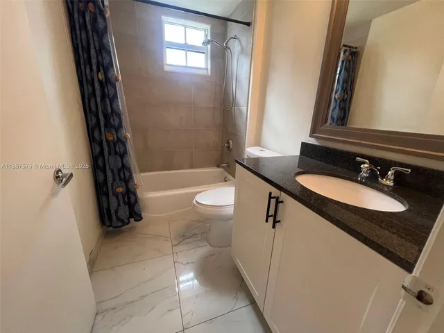 a bathroom with a granite countertop sink a toilet a mirror and bathtub