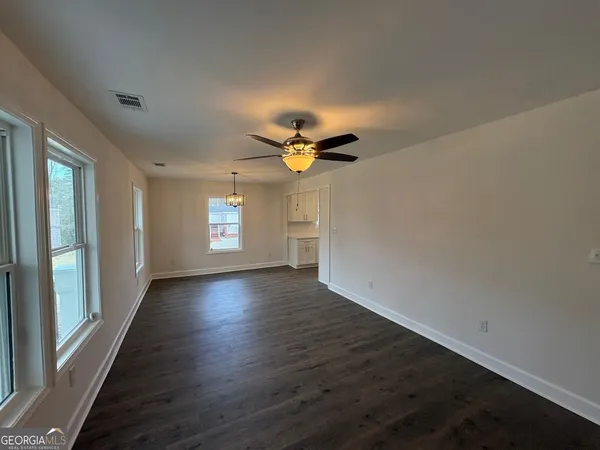 a view of empty room with wooden floor and fan