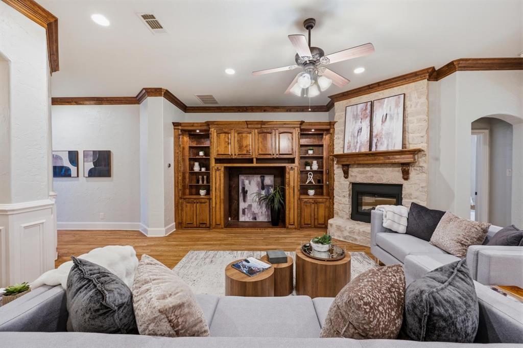 620 Highview Lane Hurst, TX 76054 - Photo 14 of 40 Living area featuring a stone-clad fireplace with a wood mantel, built-in cabinetry, wood-finish flooring, recessed lighting, and a ceiling fan
