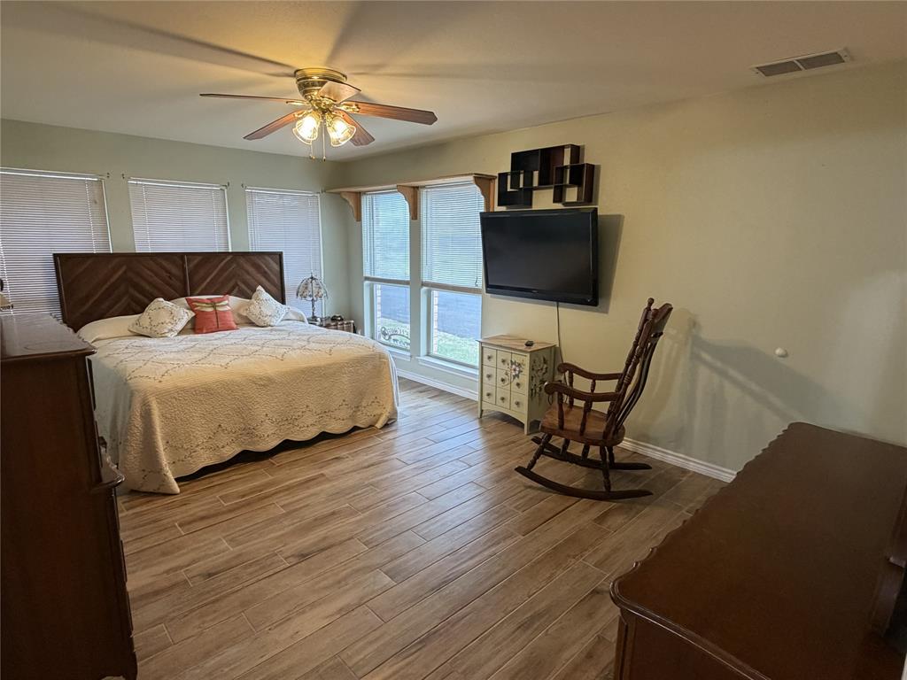 839 Walker Creek Road Ennis, TX 75119 - Photo 27 of 40 a bedroom with a bed a chair and potted plant on the dresser