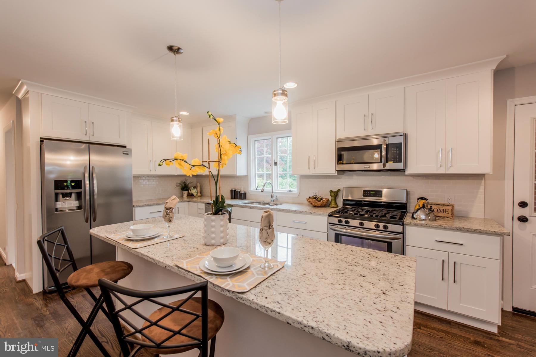 9105 Waycross Road Ellicott City, MD 21042 - Photo 2 of 27 a kitchen with stainless steel appliances kitchen island granite countertop a kitchen island hardwood floor sink stove dining table and chairs