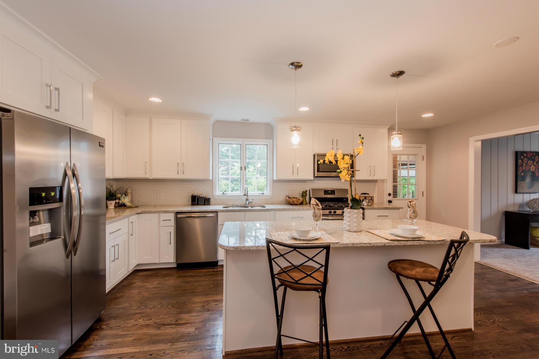 9105 Waycross Road Ellicott City, MD 21042 - Photo 6 of 27 a kitchen with stainless steel appliances kitchen island granite countertop a stove top oven a sink refrigerator and white cabinets with wooden floor