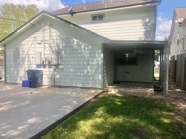 a view of yellow house with a big yard and potted plants