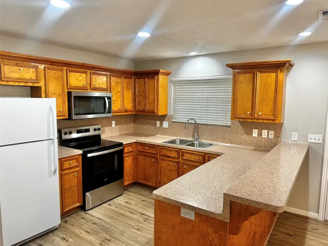 a kitchen with stainless steel appliances granite countertop a stove a sink and a refrigerator
