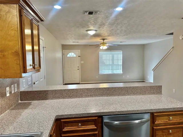 a view of kitchen and empty room with wooden floor