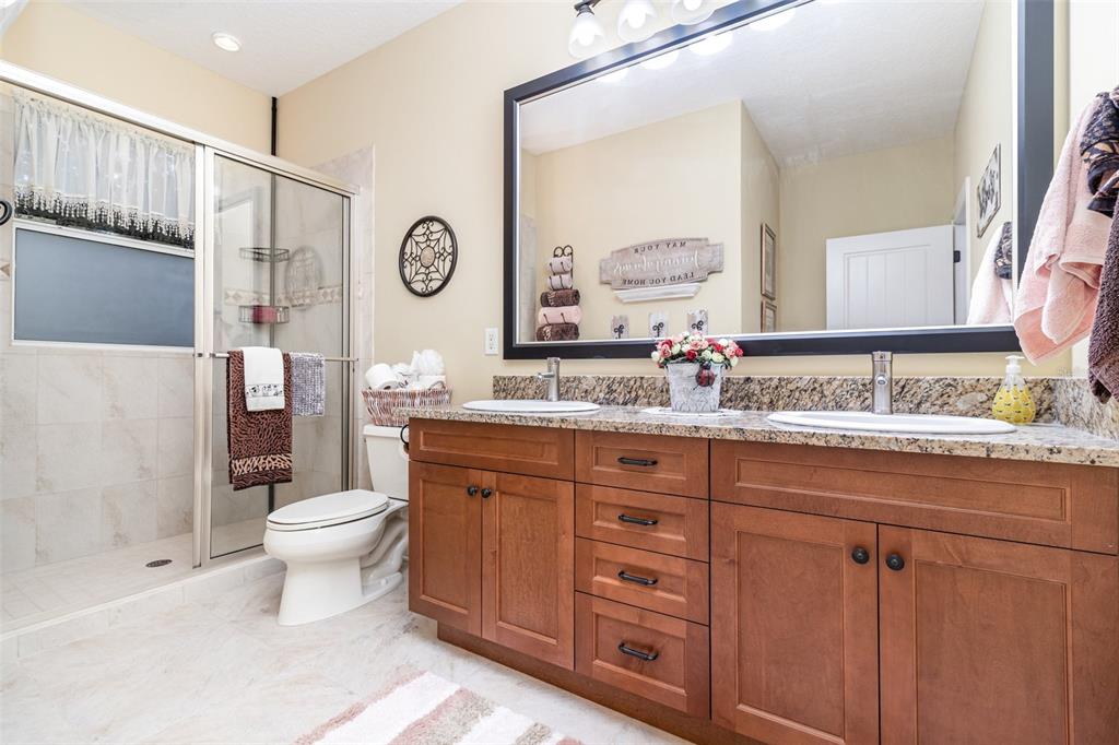 404 Long And Winding Road Howey-in-the-Hills, FL 34737 - Photo 34 of 48 a bathroom with a granite countertop toilet sink and a mirror