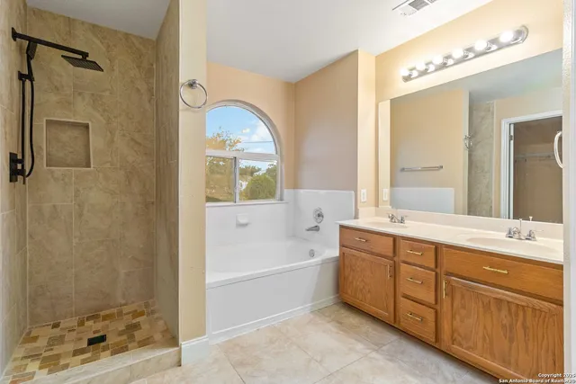 a bathroom with a tub sink mirror and shower