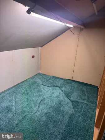 a view of an empty room with chandelier fan and kitchen view
