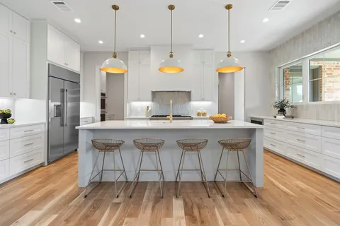 a open kitchen with stainless steel appliances granite countertop a stove a sink a oven and a dining table with wooden floor