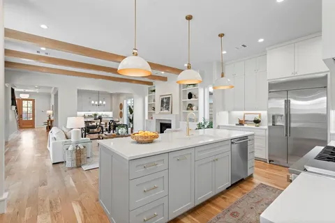 a open kitchen with a sink dishwasher stove and white cabinets with wooden floor