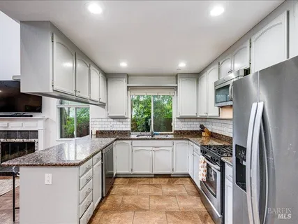 a kitchen with stainless steel appliances granite countertop a sink stove refrigerator and cabinets