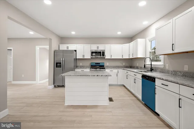 a kitchen with granite countertop white cabinets and stainless steel appliances