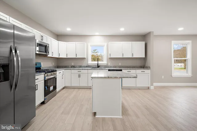 a kitchen with granite countertop white cabinets and stainless steel appliances