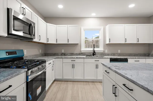 a kitchen with granite countertop white cabinets and a wooden floor