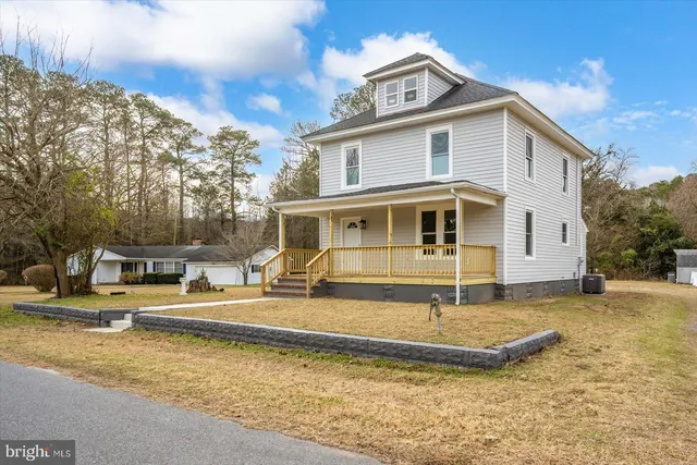 a view of a white house with a yard and large trees