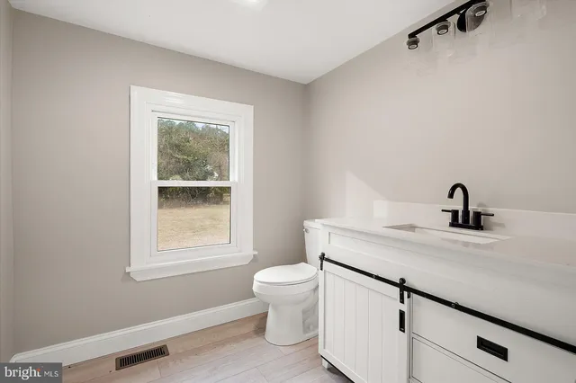 a view of a hallway with wooden floor and a bathroom