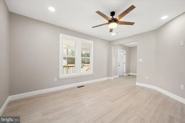 an empty room with ceiling fan and window