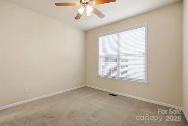 an empty room with a ceiling fan and closet area