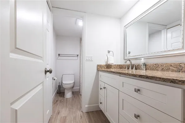 a bathroom with a granite countertop toilet sink and mirror