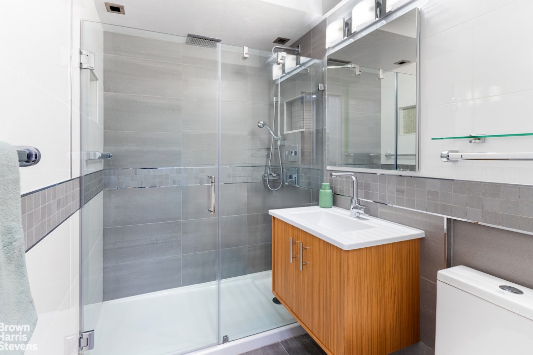 5700 Arlington Avenue, Unit 21R Bronx, NY 10471 - Photo 12 of 23 a bathroom with a sink mirror vanity and toilet