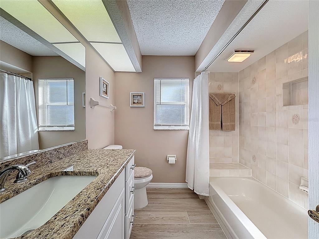 9428 Apple Dumpling Court Weeki Wachee, FL 34613 - Photo 25 of 40 a bathroom with a granite countertop sink a toilet and bathtub