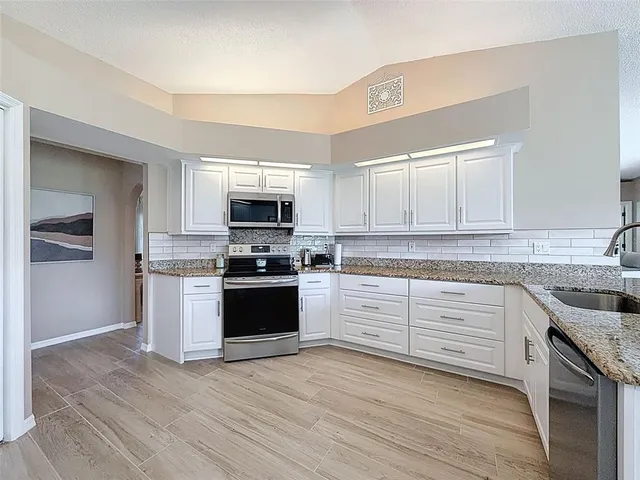 a kitchen with granite countertop white cabinets and stainless steel appliances