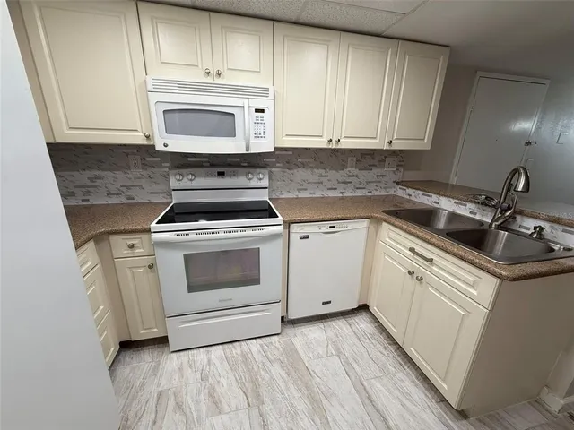 a kitchen with white cabinets sink and appliances